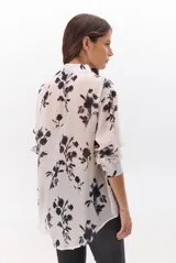 Camisa de mujer color natural con estampado floral en tonos oscuros, cuello clásico, cierre de botones frontal y mangas largas.