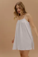 Vestido corto de algodón con diseño minimalista, breteles finos y silueta holgada con caída suave. Presenta una textura sutil en toda la prenda.