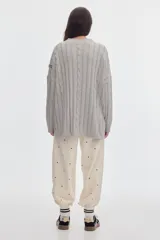 Buzo negro de tejido de ochos, con cuello redondo y diseño oversized de corte largo y amplio con tajos laterales.