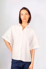 Camisa blanca de algodón con cuello camisero, corte holgado y mangas cortas con costuras en color naranja.