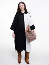 Vestido camisero largo de lino con diseño bicolor en bloques de negro y blanco, cuello camisero, cierre frontal oculto y mangas tres cuartos con silueta holgada.