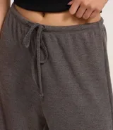 Pantalón flare negro con textura acanalada, cintura elástica con lazo y confeccionado con viscosa certificada.