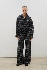 Pantalón de corte amplio y tiro medio-alto, confeccionado en tejido liviano con estampado a cuadros. Presenta cintura elastizada con lazo regulable y bolsillos laterales.