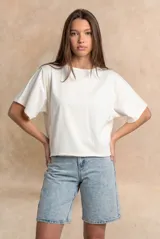 Remera oversize de algodón blanco crudo, con cuello redondo y mangas cortas anchas de corte relajado.