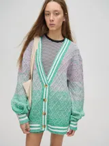 Cardigan oversize de algodón con diseño tejido a rombos en tonos degradados de marrón y blanco. Presenta cuello en V, cierre frontal con botones de madera y puños y dobladillo con rayas blancas.