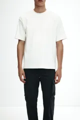 Pantalón cargo negro de nylon, corte recto y holgado, con cintura elástica y cordón ajustable. Presenta bolsillos laterales con cierre, bolsillos cargo con solapa y botones a presión en las piernas, y cordones ajustables en los bajos.