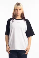 Remera de corte oversize con diseño tipo ranglan, que combina cuerpo blanco con mangas y cuello en color negro. Presenta un pequeño logo bordado en el centro del pecho.