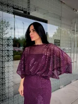 Vestido largo de fiesta color gris, confeccionado en tejido con textura calada tipo red. Presenta un diseño de silueta fluida con mangas amplias tipo murciélago y escote redondo.