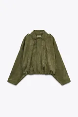 Chaqueta bomber de efecto ante en color verde militar, con cuello solapa, mangas largas con trabillas en los hombros y bajo con volumen y pliegues. Presenta cierre frontal con botones ocultos.