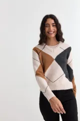Sweater de punto con diseño de rombos en tonos beige, marrón y gris oscuro. Presenta cuello en V, mangas largas y puños y ruedo acanalados.