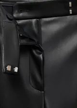 Pantalon de tiro medio efecto piel con diseño wide leg, bolsillos laterales, pinzas delanteras y cierre frontal de botón, gancho y cremallera ocultos.