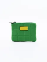 Monedero de diseño acolchado color verde con costuras en cuadrícula y detalle de parche rectangular amarillo en la parte frontal. Cuenta con cierre superior.