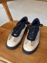Championes urbanos con diseño de estampado animal print tipo vaca, confeccionados en cuero con textura de pelo. Presentan cordones marrones, suela de goma en tono tostado y detalles en color marrón oscuro en el cuello y lengüeta.