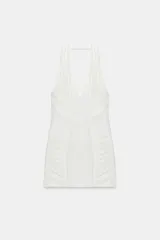 Vestido corto de cuello halter con escote en pico profundo. Presenta un diseño ajustado con paneles laterales drapeados y cierre de cremallera oculta en la espalda.