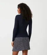 Blusa de punto acanalado en color azul marino, con cuello alto y detalle de botones dorados decorativos en los hombros. Presenta un diseño ajustado de manga larga.