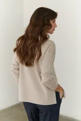 Buzo de tejido de punto acanalado en color beige, con cuello redondo, mangas largas y un bolsillo frontal aplicado en la parte inferior.