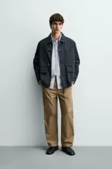 Parka de corte relajado confeccionada en mezcla de algodón color marrón. Presenta cuello solapa, cierre frontal con cremallera oculta y alamares metálicos, bolsillos de plastrón con solapa en la cadera y bolsillo de vivo en el pecho.