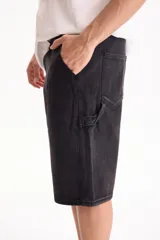 Bermuda de jean de algodón de estilo skater oversize en color negro, con diseño clásico de bolsillos y trabillas para cinto.