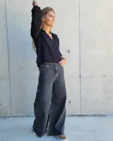 Pantalón de jean color beige, de corte recto y tiro alto, con ruedo deshilachado y cierre frontal con botón y cremallera.