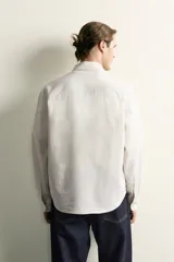 Camisa relaxed fit de algodón con estructura, cuello solapa, manga larga con puño abotonado, bolsillo de parche en el pecho y cierre frontal con botones. Presenta diseño de rayas finas.