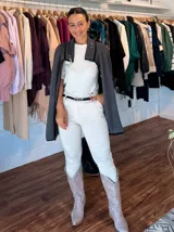 Pantalón de corte recto y tiro medio en color blanco, confeccionado en tejido elástico. Presenta cierre frontal con botón y cremallera, bolsillos laterales y viene acompañado de un cinturón fino de cuero sintético negro con hebilla metálica.