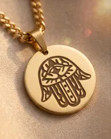 Collar doble de acero con baño de oro, compuesto por una cadena de eslabones finos y una segunda cadena con un dije circular grabado con el símbolo Hamsa.
