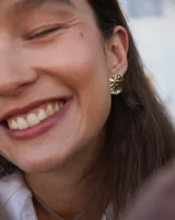 Aros tipo botón dorados con textura irregular que simula la superficie de un molusco.