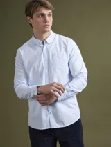 Camisa celeste de corte clásico, confeccionada en tela Oxford de algodón. Tiene cuello abotonado, manga larga con puños abotonados y bolsillo en el pecho. Marca Mersey.
