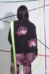 Sweater tejido y bordado a mano en lana merino, color marrón oscuro, con cuello redondo y puños ajustados. Presenta bordados florales multicolores en el frente y las mangas.