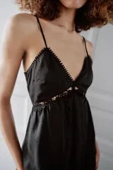 Vestido midi negro con escote en pico, tirantes finos y detalles de bordados y encaje en el escote y el bajo.