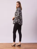 Blusa de gasa estampada con diseño geométrico multicolor, cuello a la base con escote en V y abertura frontal con botones. Presenta detalle de plisado en la parte delantera y mangas largas con sistema de ajuste mediante presilla y botón.
