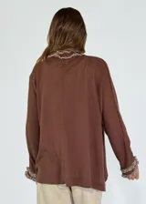 Saco color crudo de tejido de punto con detalle de volados en el frente y en los puños.