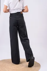 Pantalón wide leg de tiro alto confeccionado en denim negro, adornado con brillos de strass distribuidos por todo el frente.