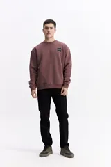 Buzo de algodón con calce oversize, cuello redondo, mangas largas con puños y bolsillos laterales. Presenta un parche cuadrado negro con lettering en el pecho y detalle de estampado en el ruedo.