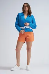 Short de jean de tiro alto, color naranja, con cierre y botón frontal, y bolsillos laterales y traseros.