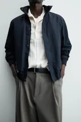 Cazadora azul marino de corte regular fit, confeccionada en tejido técnico repelente al agua. Presenta cuello subido, manga larga, bolsillos de vivo en cadera, bolsillo interior y acabados en rib en puños y bajo. Cierre frontal de cremallera oculta por solapa con botones a presión.