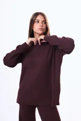 Buzo tejido de punto color negro, con cuello alto, manga larga y corte holgado con aberturas laterales en el ruedo.