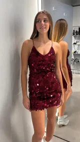 Vestido corto de fiesta color bordó, completamente cubierto de lentejuelas circulares. Presenta un diseño ajustado con escote en V y breteles finos.