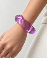 Pulsera rígida de resina translúcida en color violeta, con diseño orgánico y acabado brillante.