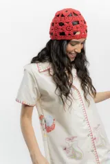 Vestido corto color crema con estampado de motivos marinos en tonos pastel, cuello camisero, cierre frontal con botones y bordado a mano en rojo en cuello, mangas y botonera.