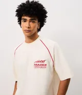 Remera oversized de color blanco marfil con detalles en rojo, cuello redondo, mangas cortas y grandes estampas tipográficas y gráficas en la espalda.