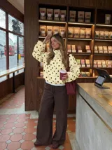 Chaqueta ligera de color amarillo con estampado de lunares negros, cuello alto, mangas largas anchas y cordón ajustable en el dobladillo inferior.