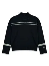 Polera de lana lambswool color negro, con cuello alto, diseño de doble raya horizontal en el pecho y rayas en los puños en color gris claro. Presenta un pin metálico con el logo de la marca en la manga izquierda.