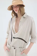 Camisa oversize de lino color beige, de calce relajado y manga larga. Presenta detalles de puntillas negras aplicadas en la parte frontal.