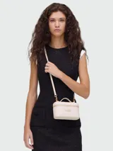 Cartera tipo vanity bag de Marc Jacobs, color beige, con cierre superior, asa corta superior y correa larga ajustable y extraíble. Presenta logo metálico dorado en el frente.