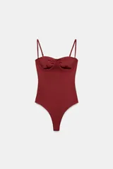Body lencero color bordó de poliamida, con escote corazón con aro, tirantes finos regulables y cierre inferior a presión.
