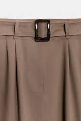 Falda midi de tiro alto en color marrón topo, con diseño abullonado en el bajo gracias a un elástico interior. Presenta pinzas frontales, cierre delantero con cremallera y un cinturón integrado con hebilla a tono.