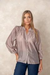 Camisa de organza blanca con cuello mao, diseño de manga larga tipo murciélago y cierre frontal con botones. Presenta un corte holgado y fluido.