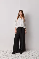 Pantalón wide leg de color negro, con cintura de tiro alto, lazo ajustable y caída fluida.