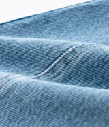 Pantalón de jean color celeste, modelo barrel, de tiro medio con trabillas para cinto, cierre frontal con botón y cremallera, bolsillos, recortes laterales y pinzas en las rodillas.